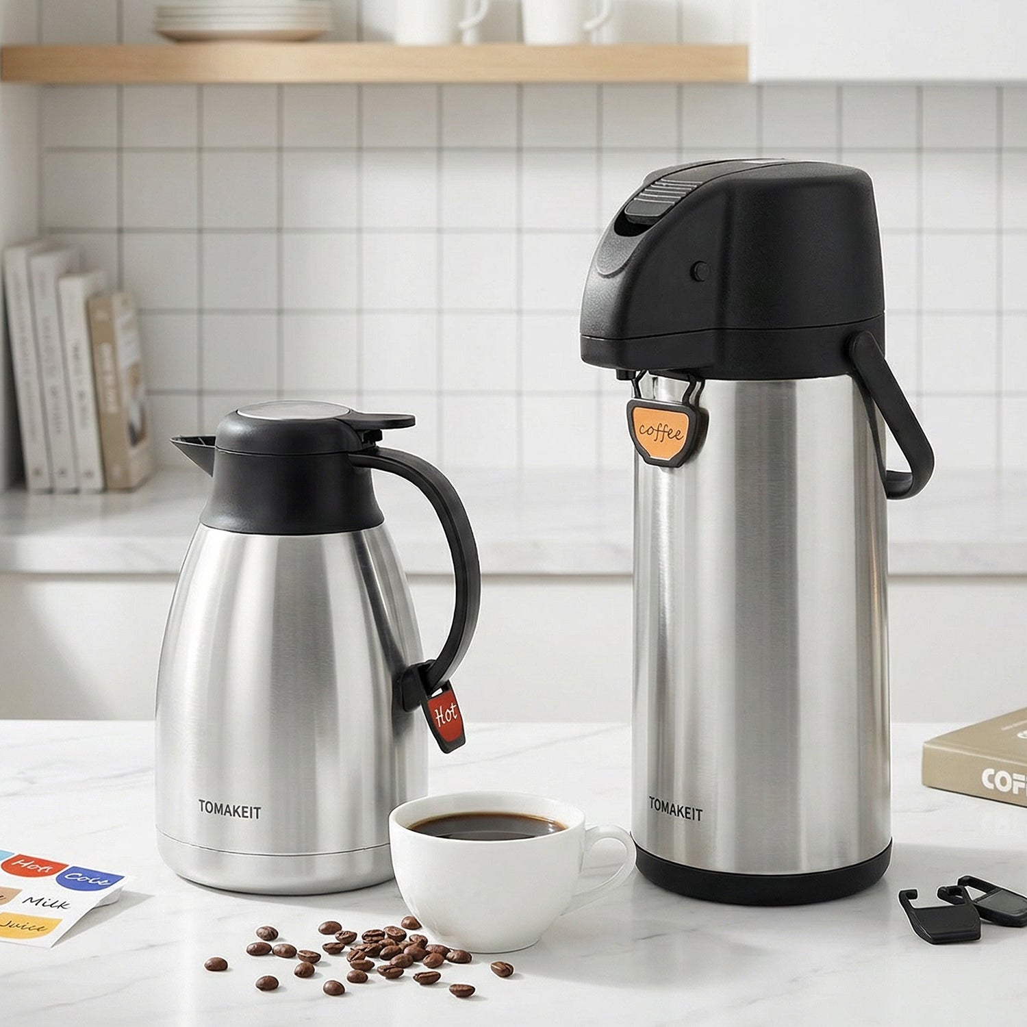 Two stainless steel coffee makers on a kitchen counter with coffee beans and a cup.